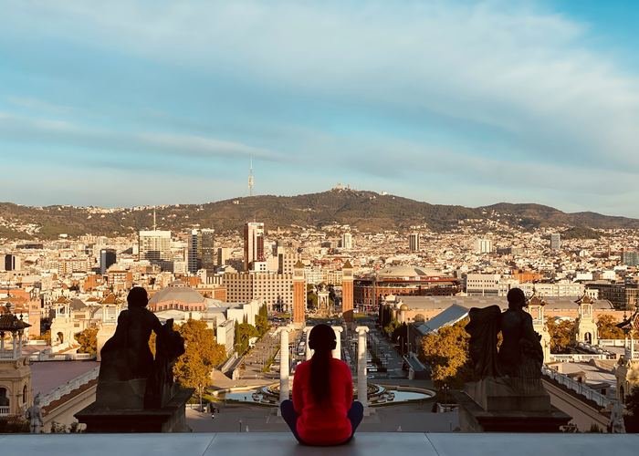 A person sitting on wide stone steps above Barcelona, looking out over the city.